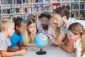Pupils and teacher looking at globe in library