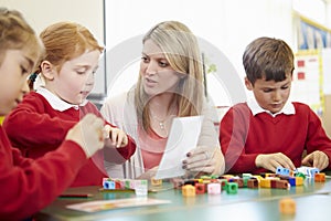 Pupils And Teacher Working With Coloured Blocks