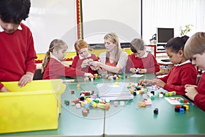 Pupils And Teacher Working With Coloured Blocks