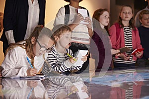 Pupils On Trip To Museum Looking At Map And Making Notes