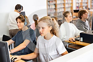 Pupils using computers at lesson, teacher teaching them in class room