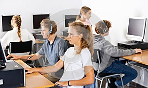 Pupils using computers at lesson, teacher teaching them in class room