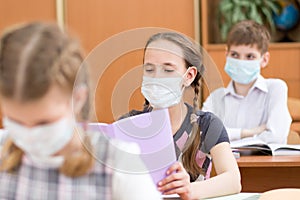 Pupils wearing protection mask to prevent virus during lesson in classroom