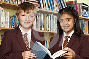 Pupils Wearing School Uniform Reading Book In Library