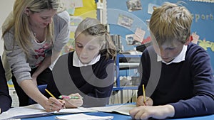 Pupils Working At Table With Teacher Helping Them