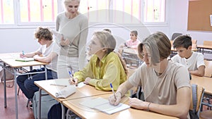 Pupils write in notebooks while sitting at desks in a school class