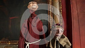 Puppets dressed as monks next to framed art