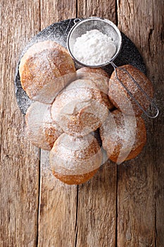 Pupular street food Bunuelos sprinkled with powdered sugar close-up. Vertical top view photo