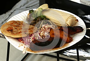 Pupusa with chorizo, sweet plantains, coleslaw, and tamales