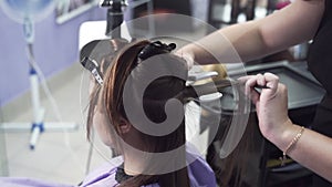 Purchase plan slow-motion shooting stylist hairdresser straightens the client`s hair after keratin straightening with a