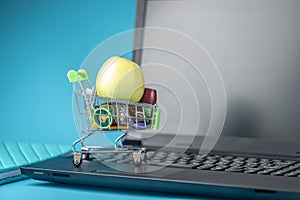 Daily purchases in the shopping cart on the laptop keyboard on a blue background. Concept of shopping in online stores photo