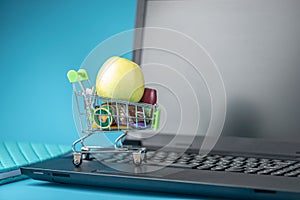 Daily purchases in the shopping cart on the laptop keyboard on a blue background. Concept of shopping in online stores