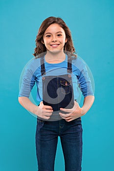 Pure beauty. Little girl with long hair. Kid happy cute face with adorable curly hair stand over blue background. Beauty