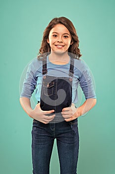 Pure beauty. Little girl with long hair. Kid happy cute face with adorable curly hair stand over blue background. Beauty