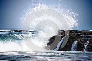 Pulito blu acqua da Pacifico Oceano costiero onde lasciare un schizzi sul il mare Costa rocce coperto conchiglie 