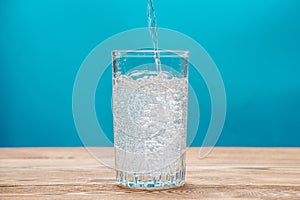 Pure carbonated water with bubbles in a glass on a blue background