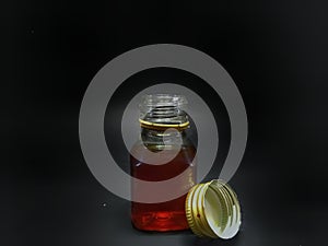 Pure honey in a glass bottle brown coloured with a dark background and selective focus.