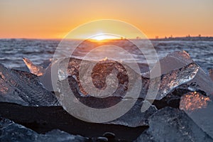 Pure Ice Shining on Black Volcanic Sand at Sunset. Icebergs from Glacier in Sun Rays. Clear Ice in Ocean Waves. Famous