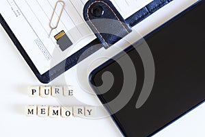 Pure memory lettering next to an open blank notebook, micro-sd memory card, smartphone and ejector for ejecting a SIM card. photo