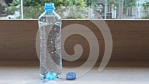 Pure mineral water in a plastic bottle with gas bubbles rising up. Sparkling bottled water on a table near window with