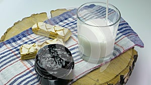 Pure natural milk into a glass, dairy products with pastries on a wooden board