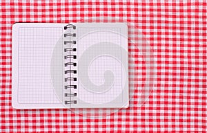 Pure notebook for recording menu, recipe on red checkered tablecloth tartan.