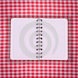 Pure notebook for recording menu, recipe on red checkered tablecloth tartan.