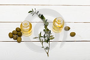 Pure olive oil and green olives on wooden surface