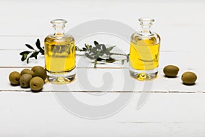 Pure olive oil and green olives on wooden surface