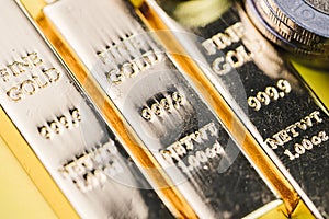 Pure 999.9 shiny fine gold bullions ingot bars with money coins, closed up macro shot as financial asset, investment and wealth c
