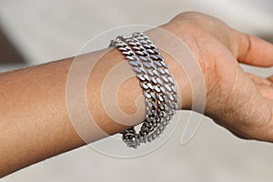 Pure silver chain that is worn as a bracelet on hand exposed to natural light. Silver chain with details of chain links