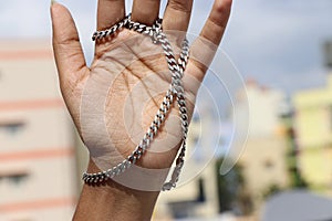 Pure silver chain that is worn in hand as a fashion jewelry against a natural background