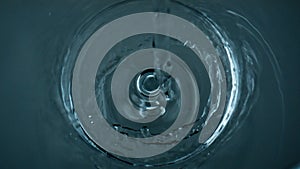 Pure water filling glass top view closeup. Crystal clear liquid stream bubbling