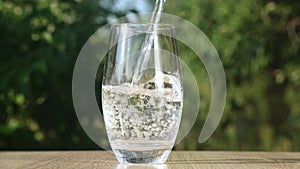 Pure Water Poured Into Glass Closeup on Green Nature Background in the morning