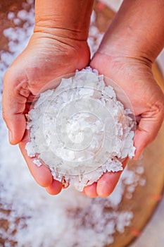 Pure white crystals salt, rock salt in women hands on crystals backgrounds. Top view, close-up. Traditional rock salt making of Bo