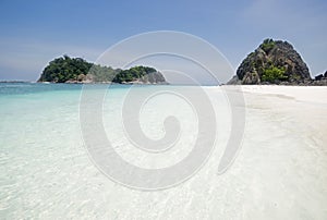 Pure white fine sandy sand & shallow blue water with speed boat & cloudless sky at Pulau Lima Besar island, Johor, Malaysia photo