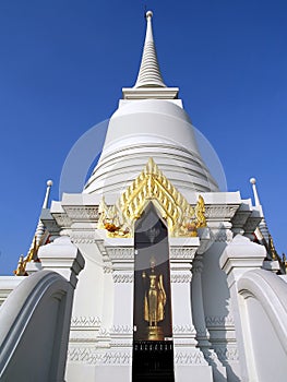 pure white pagoda with golden thai pattern carving gable and gold buddha statue standing in glass cabinet photo