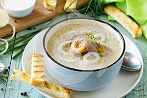 Puree soup mushrooms with croutons in a bowl on a kitchen wooden table