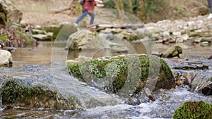 Purest mountain creek in the forest. Stream of water moves between the stones covered with moss. Small river with rocks