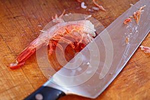 Purified boiled shrimp and a kitchen knife lie on a cutting board