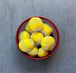 Purified boiled yellow potatoes in a red bowl on a gray background