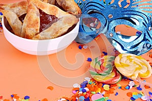 Purim background with carnival mask, party costume and hamantaschen cookies.