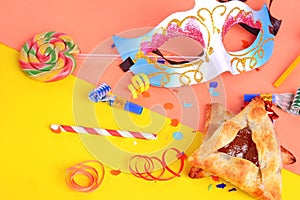 Purim background with carnival mask, party costume and hamantaschen cookies.