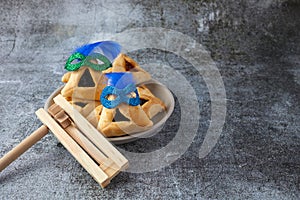 Purim celebration concept with hamantashen cookies, Purim mask and toy noisemaker on grey background