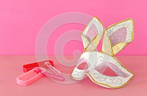 Purim celebration concept & x28;jewish carnival holiday& x29; with cute rabbit mask and noisemaker over wooden table