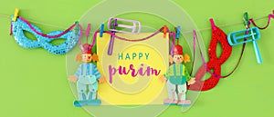 Purim celebration concept & x28;jewish carnival holiday& x29; with note, clown and noisemaker over wooden green background.