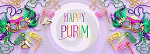 Purim celebration concept jewish carnival holiday over purple wooden background. Top view, Flat lay