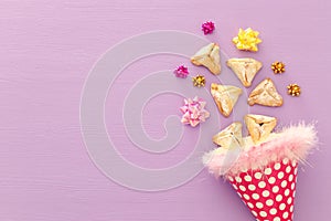 Purim celebration concept & x28;jewish carnival holiday& x29;. Traditional hamantaschen cookies over purple wooden table.