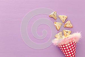 Purim celebration concept & x28;jewish carnival holiday& x29;. Traditional hamantaschen cookies over purple wooden table.