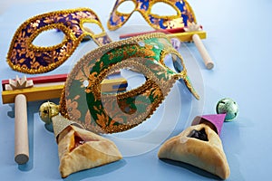 Purim celebration concept. Mask with hamantashen cookies and gragger. Jewish carnival background.